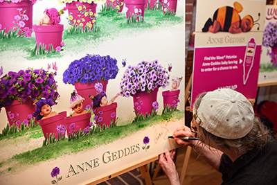 Anne Geddes autographing the Wave Petunias print featuring babies and flowers