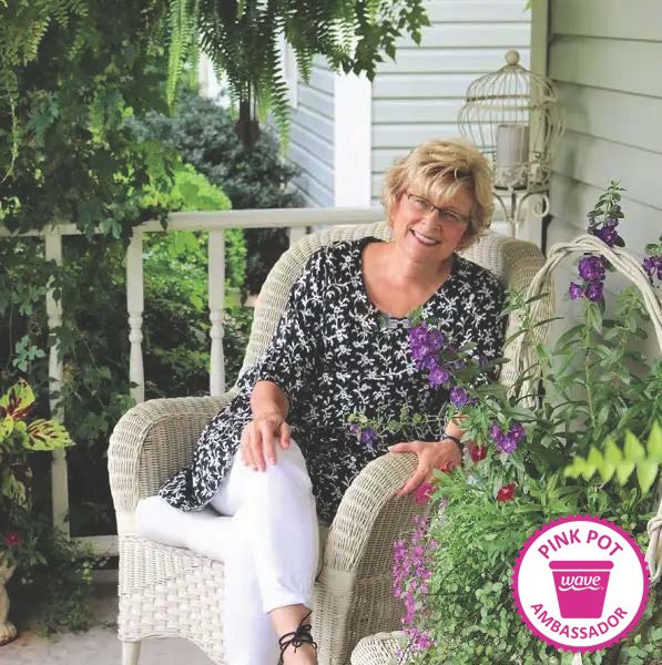 Wave Pink Pot Ambassador for October 2022 Linda sites outside on her porch with flowers