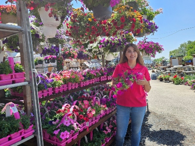 Woman in a pink shirt in a garden center holding flowers