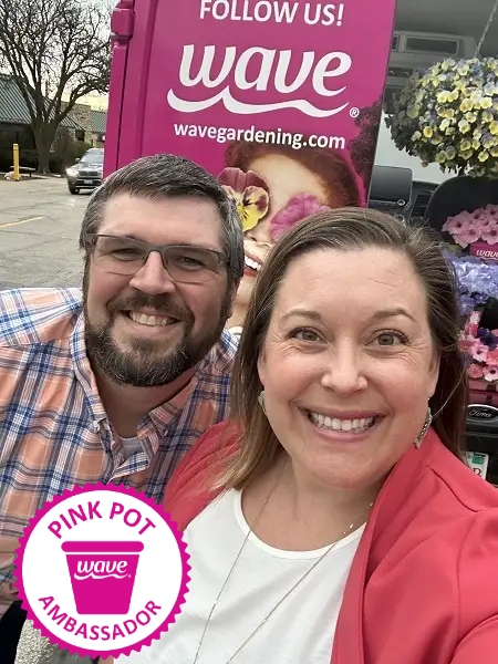 Man and women outside smiling with a pink van full of colorful flowers