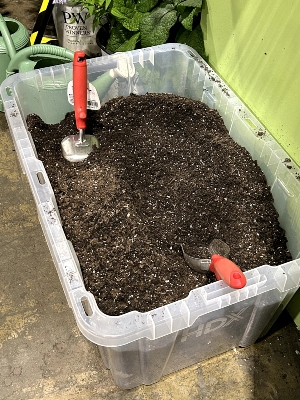 Top soil in a plastic container with trowels