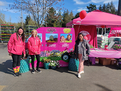 Three ladies dressed in pink in front of a Wave Petunia display