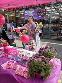 Kids and adults gather at a pink tent with balloons