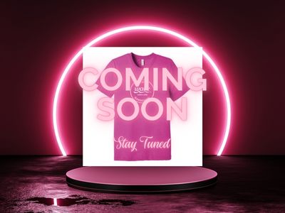 A dark stage with neon lights that say Coming Soon with a pink shirt in the background