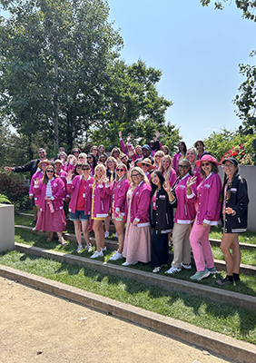 Group of people wearing pink waving in a garden